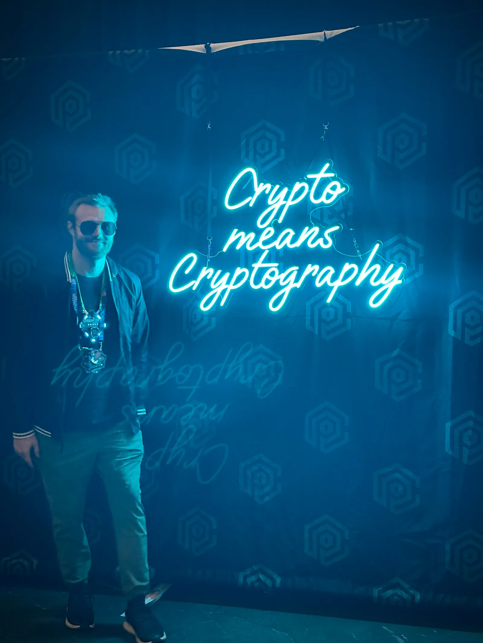 The author at DEF CON next to a neon sign reading Crypto means Cryptography