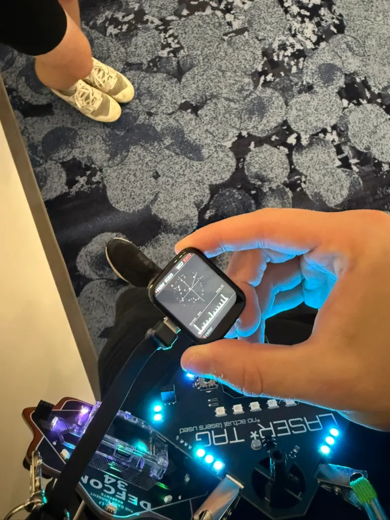 Holding the ESP32 badge at DEF CON with the radar screen showing live Wi-Fi and BLE counts